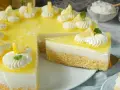 Erfrischende joghurt-torte mit biskuitboden, dekoriert mit Zitronenspalten und Sahnetupfern.
