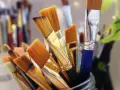 Un pot rempli de pinceaux aux poils orangés, prêts à être utilisés avec un nettoyant peinture acrylique.
