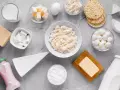 Różnorodne produkty bogate w wapń: mleko, sery, jogurt, masło, jajko i wafle ryżowe.