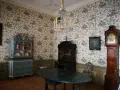 Wnętrze Uphagen House: zabytkowy zegar, szafka, stół i tapeta z ptakami.