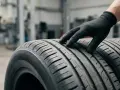 Mano guantata esamina il battistrada di pneumatici nuovi, un dettaglio importante per capire quali pneumatici scegliere per la tua auto.