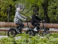 Dwaj młodzi ludzie cieszą się jazdą na rowerach elektrycznych. Dofinansowanie do roweru elektrycznego sprawia, że ekologiczny transport jest dostępny dla każdego.
