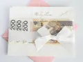 Elegancka koperta z napisem "Młodej Parze", ozdobiona banknotami 200 zł i białą wstążką. Idealny sposób, jak udokumentować pieniądze z wesela.