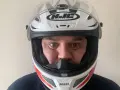 Hombre con casco HJC blanco y rojo, listo para elegir su equipo de moto.