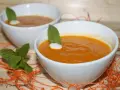 Dos cuencos blancos con crema de calabaza naranja, decorados con menta y un toque de nata.