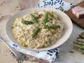 Un cremoso risotto con asparagi e pancetta, guarnito con punte di asparagi freschi e parmigiano.