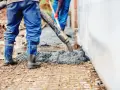 Pracownicy wylewają beton na zbrojenie. Warto wiedzieć, ile waży kubik betonu, by zaplanować transport i obciążenie konstrukcji.