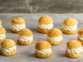 Douzaines de délicieux choux à la crème, garniture généreuse de crème fouettée, sur fond gris.