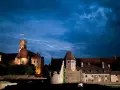 Potężny zamek krzyżacki nocą, część szlaku zamków krzyżackich, z polską flagą na wieży.