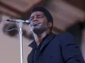 Le chanteur funk français James Brown, en sueur, chante passionnément dans un microphone.