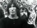 Quatre musiciens aux cheveux longs, dans un style musical Pink Floyd, posent devant un feuillage.