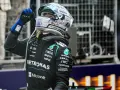 Piloto de F1 con casco y guantes azules levanta el dedo índice, celebrando una victoria en la carrera F1 Mónaco.