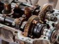 Mechanizm zmienne fazy rozrządu w silniku, z widocznymi wałkami, kołami zębatymi i śladami oleju.