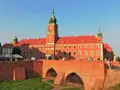 Słoneczny dzień na placu zamkowym w Warszawie. Ludzie odpoczywają na murze przy Zamku Królewskim.