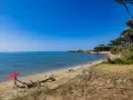 Torre Astura e la sua spiaggia, con un ombrellone rosso e una persona che si rilassa su un tronco.