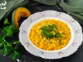 Piatto di pasta e zucca alla napoletana, guarnito con prezzemolo fresco e parmigiano. Accanto, una fetta di zucca e un mazzetto di prezzemolo.