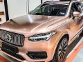 En lyxig Volvo XC90 med en glänsande roséguld folierad bil. Bilen står i ett garage med orange linjer på golvet.