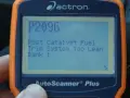 An orange and blue Actron AutoScanner Plus displays error code P2096: Post Catalyst Fuel Trim System Too Lean Bank 1.