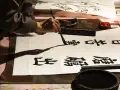 Une main manie un pinceau pour créer de la calligraphie chinoise sur du papier blanc. Des caractères noirs se déploient, témoins d'un art ancestral.