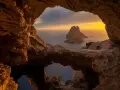 Widok z jaskini na skalistą wysepkę Es Vedrà, jedną z najpiękniejszych wysp Balearów, o zachodzie słońca.