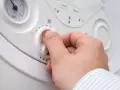 Mano che gira la manopola per alzare la temperatura della caldaia. Si vede il quadrante della pressione.