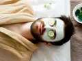 Man with a face mask and cucumber slices on eyes, relaxing. Wondering how long to keep face mask on for best results.