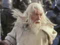 Gandalf z długą, siwą brodą i włosami, w białym płaszczu, gotowy do walki.