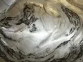 Textura metálica con trazos negros y finas líneas, evocando un grabado en carborundum.