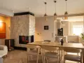 Przytulny salon z kominkiem i jadalnią w stylu klasycznym. Drewniany stół z krzesłami, kanapa i nowoczesny kominek tworzą ciepłą atmosferę.