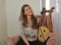 Uśmiechnięta kobieta trzyma instrument muzyczny, który wygląda jak skorupa żółwia.