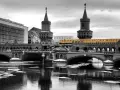 Gelbe U-Bahn fährt über die Oberbaumbrücke in Berlin. Eisschollen treiben auf dem Wasser.