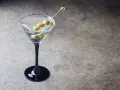 Klasyczny Dirty Martini przepis: schłodzony gin, wermut i oliwki na wykałaczce w eleganckim kieliszku.