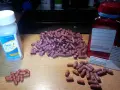 Duża garść różowych kapsułek, przypominających salazę, leży obok butelki leku Asacol.