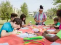 Des enfants créatifs participent à un atelier d'art en plein air, une activité typique d'un centre de loisirs ou d'un camp d'été, peut-être dans le cadre d'un programme ACM BAFA.