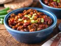 Herzhaftes Chili con Carne nach einem Rezept von Jamie Oliver, garniert mit Frühlingszwiebeln, in einer blauen Schüssel.