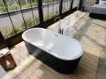 Vasca da bagno freestanding nera e bianca, con rubinetteria a colonna. L'altezza della vasca da bagno in muratura è ideale per un bagno moderno.