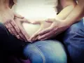 Dłonie tworzą serce na brzuchu w 5 miesiącu ciąży. Czekamy na nasze maleństwo.