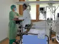 Pflegekraft unterstützt Patientin bei der Reha nach Intensivstation. Sie üben das Aufstehen.