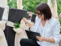 Kobieta w białej marynarce dopina wstążkę na krześle. Czy warto wynająć wedding plannera na samą koordynację dnia ślubu?