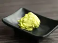 Zielona pasta, czyli co to jest wasabi, na czarnej, kwadratowej miseczce.