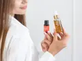 Kobieta prezentuje dwa produkty do pielęgnacji włosów, pokazując jak nakładać serum na włosy dla ich regeneracji i nawilżenia.