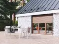 Drewniany taras z meblami i oknem z zasuniętymi roletami chroniącymi przed upałem.