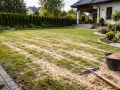 Piaskowanie trawnika w toku. Grabie i wiadro z piaskiem czekają na dalsze prace.
