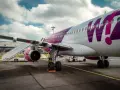 Samolot Wizz Air z fioletowym logo na lotnisku, z drabiną przy skrzydle.