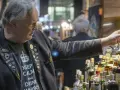 Mann mit "Keep Calm and Drink Whisky"-Shirt und vielen Ansteckern auf einer Whiskey Messe, der eine kleine Box hält.