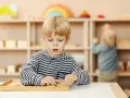 Chłopiec skupiony na zadaniu z materiałem Montessori. Ta metoda polega na samodzielnym odkrywaniu świata przez dziecko.