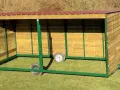 Abri pour chevaux en bois, mobile et sans permis de construire, avec toit rouge et structure verte.