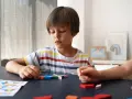 Uczeń z autyzmem w szkole średniej, skupiony na układaniu kolorowych klocków.