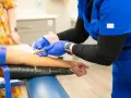 Pielęgniarka w niebieskim uniformie podczas kursu medycyny pracy pobiera krew.