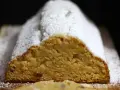 Ein saftiger Quarkstollen mit Marzipan, bestäubt mit Puderzucker, wartet auf den Anschnitt.